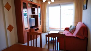 Olohuone, jossa on sohva, televisio ja ruokapöytä.