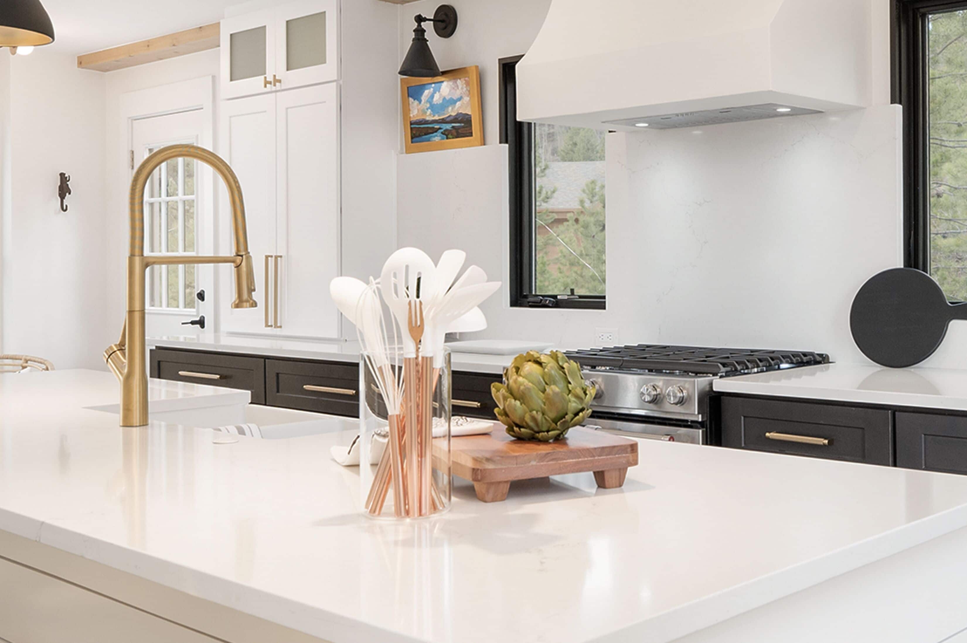 A modern kitchen with a white countertop, a gas stove, a wooden cutting board, and an artichoke centerpiece.