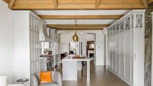 Une cuisine spacieuse avec des meubles blancs, un îlot central et un plafond en bois.
