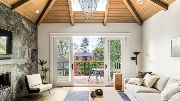Un salon moderne doté d’une cheminée, d’un canapé, d’une table basse et offrant une vue sur l’extérieur grâce à de grandes portes coulissantes.