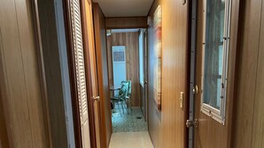 A hallway with wooden doors, a patterned rug, and a view into a dining area with chairs and a table.