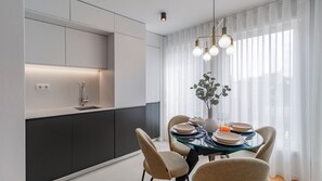 A modern kitchen with a built-in sink, a dining area with a glass table, and a vase with a plant. - Downtown Bliss w/ AC by LovelyStay (Porto)