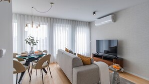A modern living room with a sofa, TV, dining table, and chairs. - Downtown Bliss w/ AC by LovelyStay (Porto)