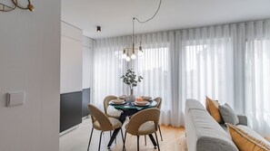 A modern living room with a dining area, featuring a sofa, chairs, a TV, and a dining table with a vase of flowers. - Downtown Bliss w/ AC by LovelyStay (Porto)