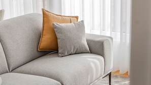 A sofa with a textured fabric and two pillows, one with a contrasting trim. - Downtown Bliss w/ AC by LovelyStay (Porto)