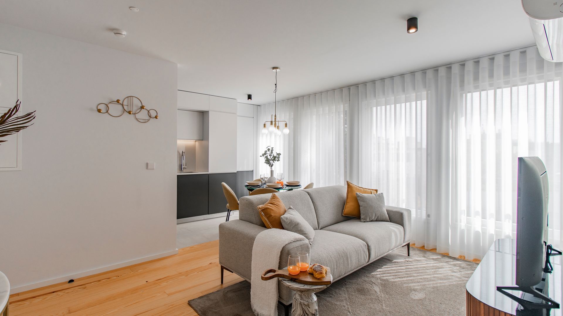 A modern living room with a grey sofa, a coffee table, and a TV.