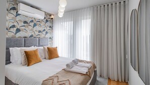 A modern bedroom with a large bed, a grey headboard, and a patterned wallpaper. - Downtown Bliss w/ AC by LovelyStay (Porto)