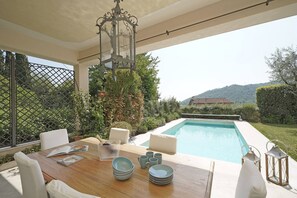 An outdoor dining area with a pool, white furniture, and a decorative lantern. - Villa San Carlo - Gardagate (Roè)