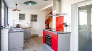 Una cocina compacta con armarios grises y rojos, un microondas y un horno empotrado.