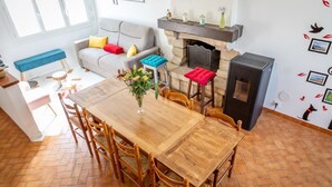 Una sala de estar acogedora con chimenea, un comedor con mesa y sillas de madera, y un sofá con cojines coloridos.