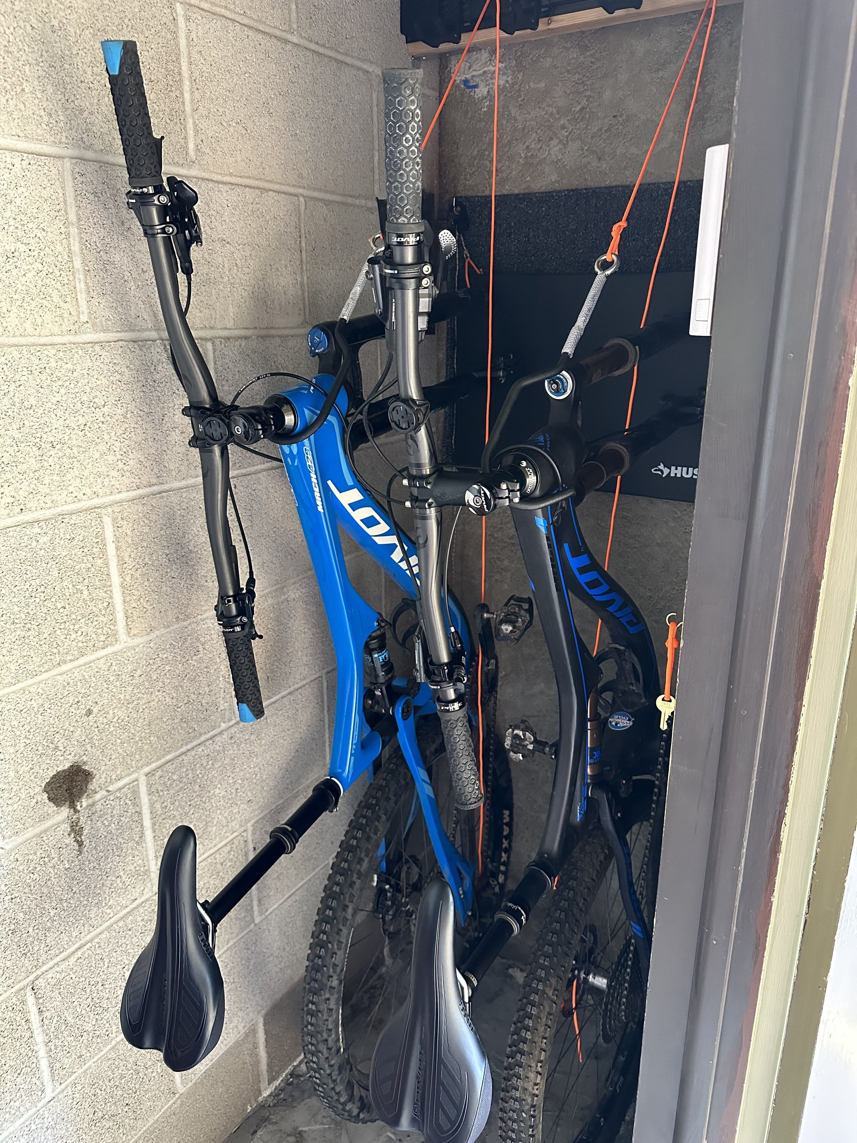 A blue mountain bike with a black seat and handlebar grips, mounted on a wall with a brick pattern.