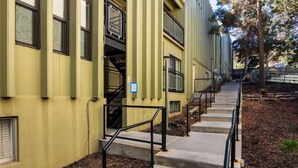 A building with a yellow facade, multiple windows, and a staircase with black railings leading to an upper level. - Summer at Resort - Pool, Hot Tub, Sauna, AC & Gym (Park City)