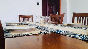 A dining table set with plates, glasses, and a patterned table runner. - Greenzone BnB (Kiambu County)