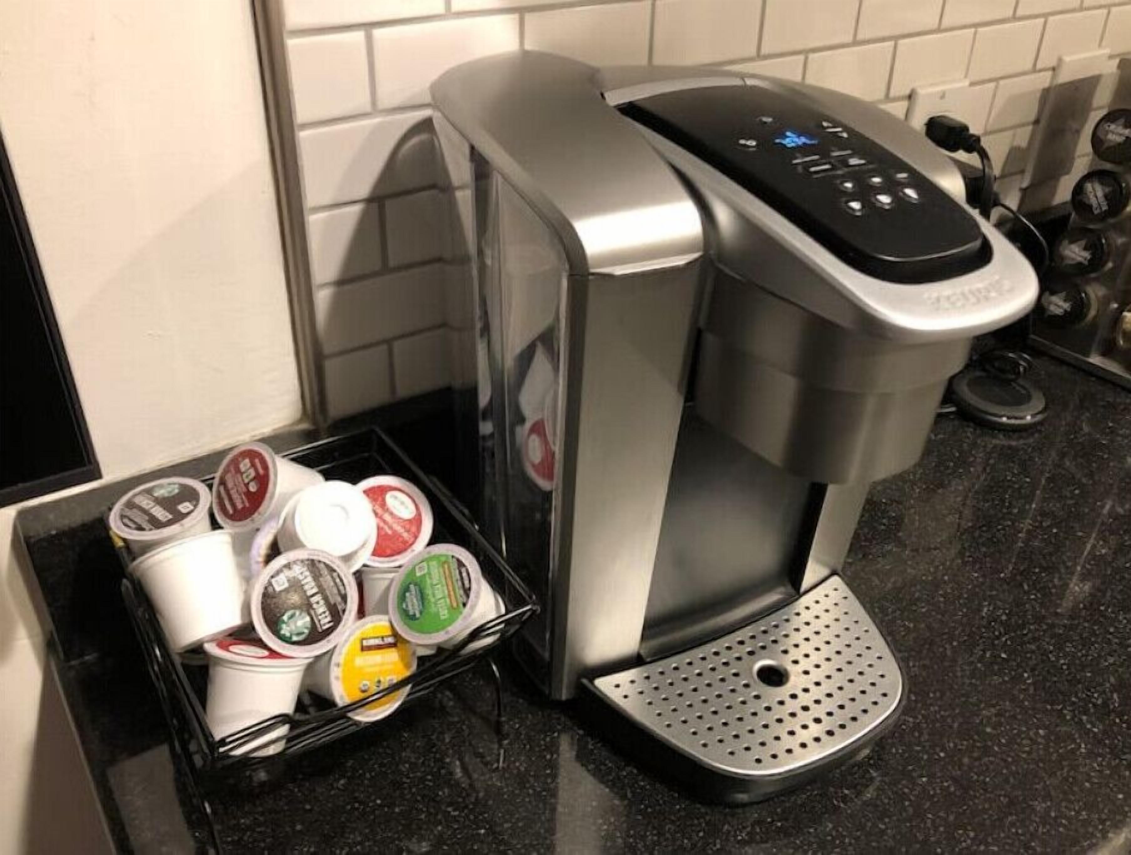 Une machine à café dotée d’un bac de récupération et d’un compartiment pour les dosettes de café.