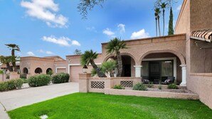 A courtyard with a well-maintained lawn, palm trees, and a building with arched doorways and a covered patio area. - Quiet & Close to Everything in Scottsdale, Arizona (Scottsdale)
