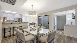 A modern kitchen with stainless steel appliances, a glass dining table with chairs, and a pendant light. - Quiet & Close to Everything in Scottsdale, Arizona (Scottsdale)