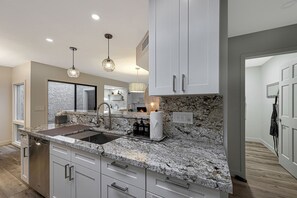 A modern kitchen with granite countertops, stainless steel appliances, and pendant lighting. - Quiet & Close to Everything in Scottsdale, Arizona (Scottsdale)