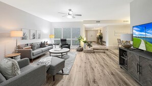 A modern living room with a grey sofa, a coffee table, and a TV on a wooden cabinet. - Quiet & Close to Everything in Scottsdale, Arizona (Scottsdale)