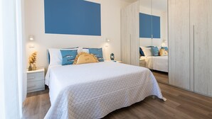 A bedroom with a bed, bedside tables, a mirror, and a wardrobe. - Nida 18 - Two Bedroom Apartment, Sleeps 6 (Cattolica)
