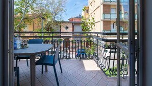 A balcony with a table and chairs, a view of parked cars, and buildings in the background. - Nida 18 - Two Bedroom Apartment, Sleeps 6 (Cattolica)