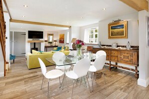 A spacious living room with a glass dining table, white chairs, and a yellow sofa. - Colleton East Wing - Three Bedroom Villa, Sleeps 6 (Rackenford)