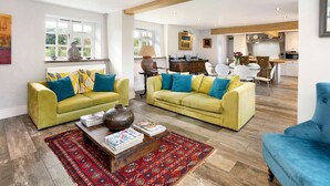 Ein geräumiges Wohnzimmer mit zwei gelben Sofas, einem blauen Sessel und einem Couchtisch mit Zeitschriften.
