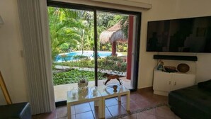Una habitación con puerta de vidrio que da a una zona de piscina, un armario blanco y un sofá negro.