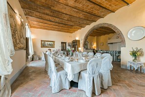 A dining area with a long table set for a meal, brick ceiling, and a rustic archway.