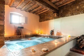 A spa area with a hot tub, candles, and a stone wall. - Villa Monte Nero - Nine Bedroom Villa, Sleeps 22 (Volterra)