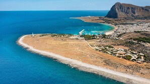 An aerial view of a coastal area with a beach, a lighthouse, and a mountainous backdrop. - Camilla Canna - Three Bedroom Villa, Sleeps 6 (Cala Rossa)