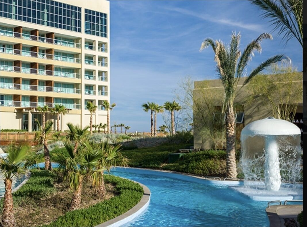 Un hôtel doté d’une piscine, de palmiers et d’une fontaine.