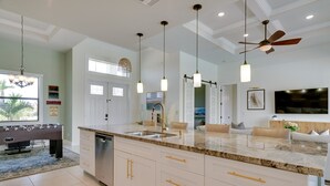 Een moderne keuken met een groot schiereiland, witte kasten en hanglampen.