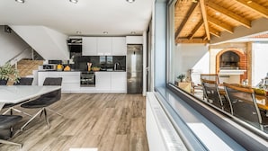 Una cocina moderna con gabinetes blancos, un refrigerador de acero inoxidable y una zona de comedor con mesa y sillas.