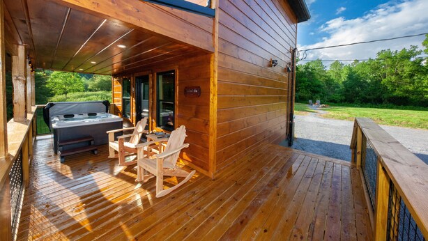 Une terrasse en bois avec un jacuzzi, des sièges et un espace abrité.