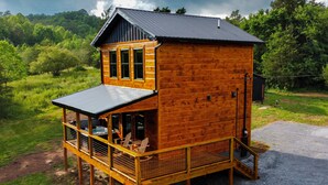 Une cabane en bois dotée d’un balcon, d’un jacuzzi et d’une terrasse couverte.