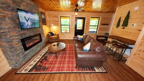 L’intérieur d’un chalet accueillant, avec une cheminée, un canapé en cuir et des murs en bois.