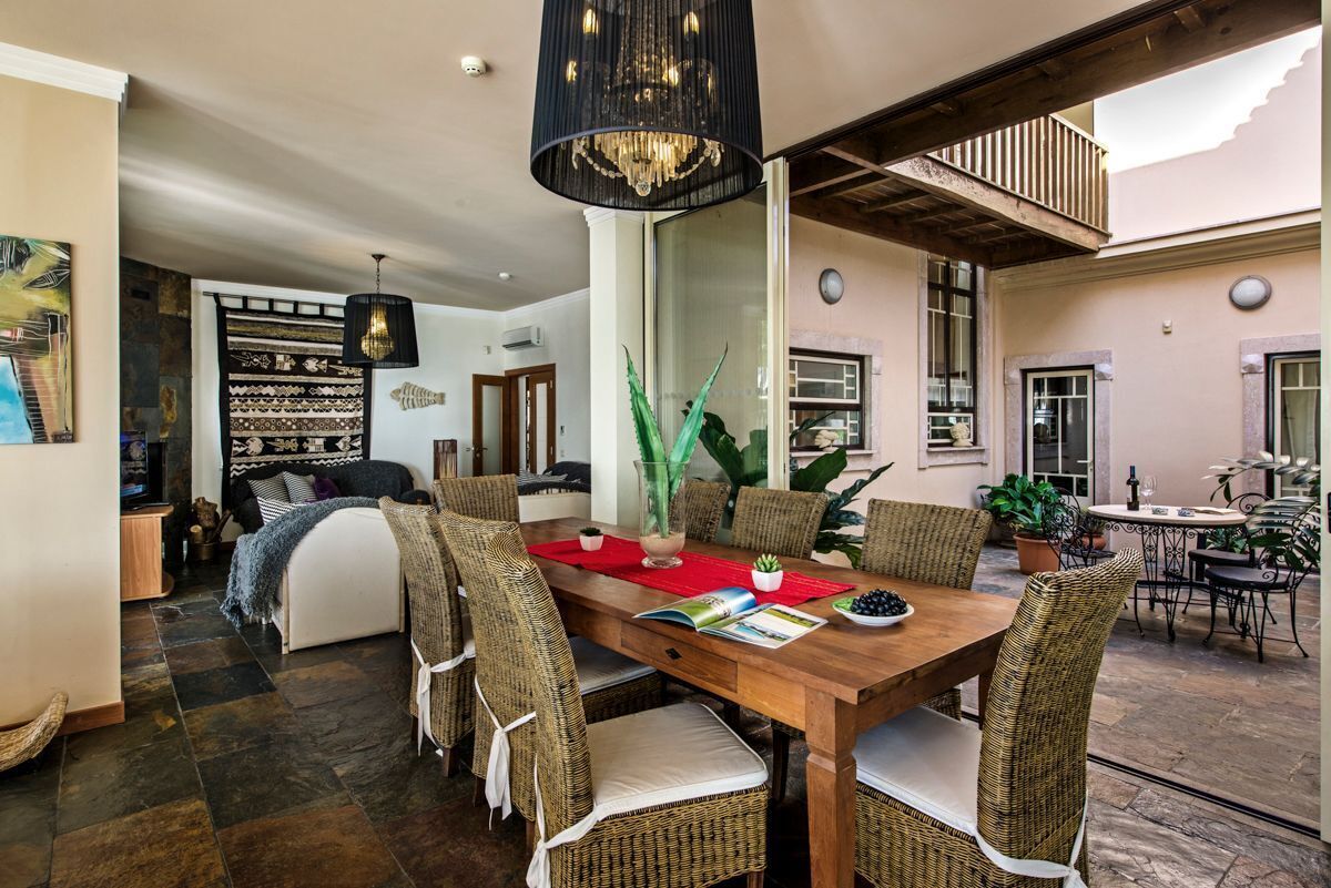 A dining area with a wooden table, wicker chairs, and a chandelier.