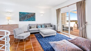 Un salon moderne avec un canapé gris, un petit fauteuil blanc et un tapis bleu.