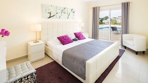 Une chambre d’hôtel avec un lit, une table de chevet, une lampe, une chaise et une vue sur une piscine.