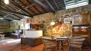 A rustic interior with stone walls, wicker furniture, and a stone fireplace. - Villa Estora - One Bedroom Villa, Sleeps 2 (Estorãos)