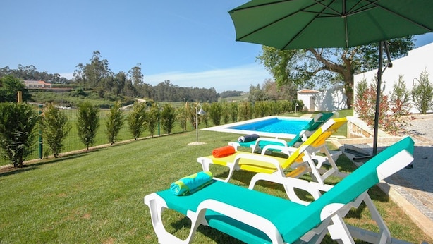 A poolside area with lounge chairs and an umbrella. - Villa Anabela - Three Bedroom Villa, Sleeps 6 (Povoa de Varzim)
