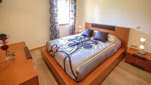 A modern bedroom with a large bed, wooden headboard, and a nightstand with a lamp. - Villa Anabela - Three Bedroom Villa, Sleeps 6 (Povoa de Varzim)