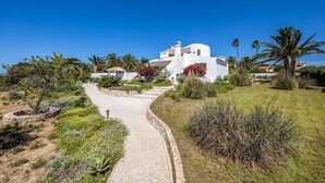 A white villa with a curved driveway, surrounded by palm trees and a well-maintained garden. - Villa Lua - Three Bedroom Villa, Sleeps 6 (Lagoa)