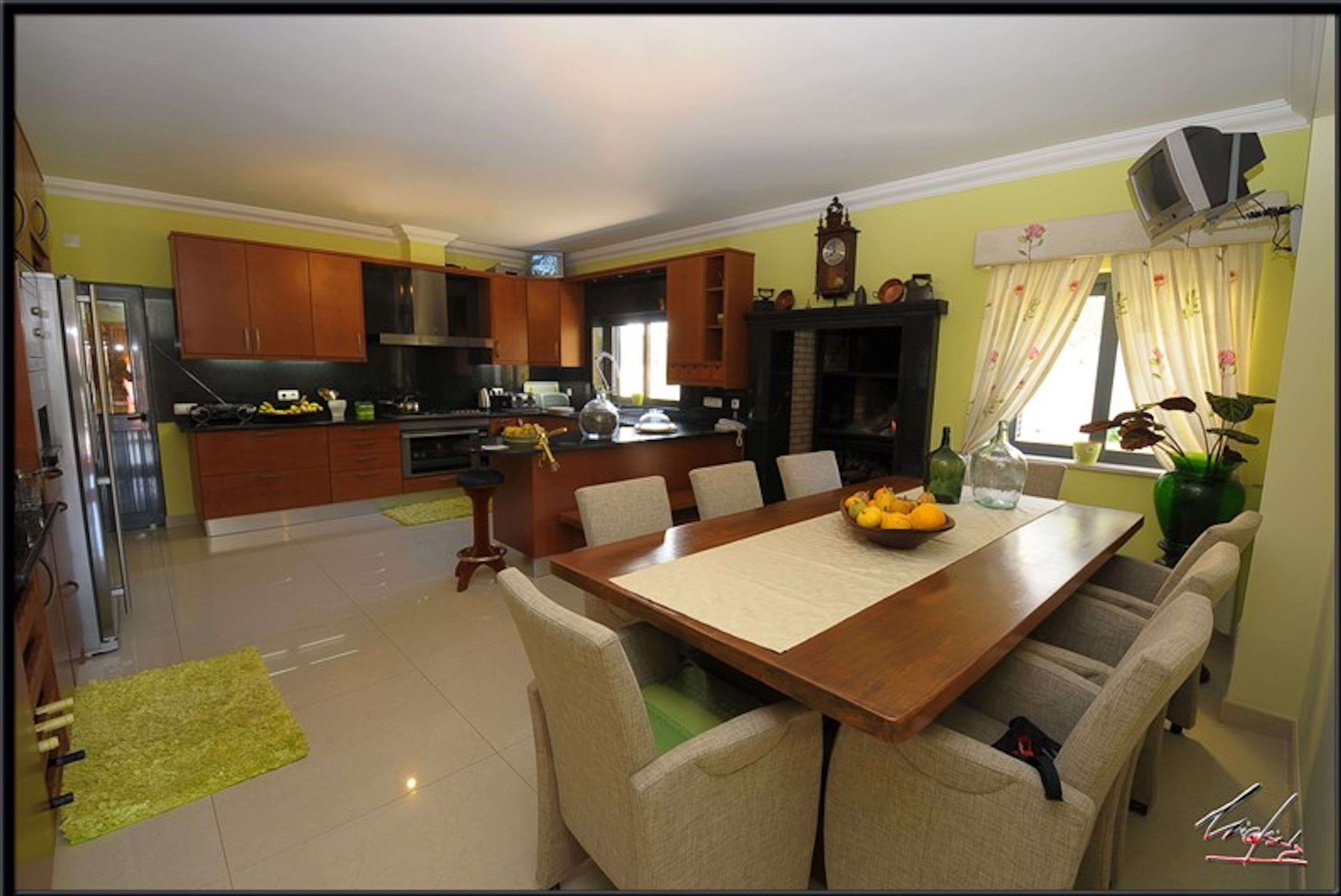 Cozinha moderna com armários de madeira, mesa de jantar com cadeiras e lareira.