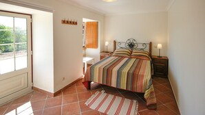 A bedroom with a bed, two bedside tables, a nightstand, a window, and a door. - Villa Anisa - Four Bedroom Villa, Sleeps 8 (Estorãos)