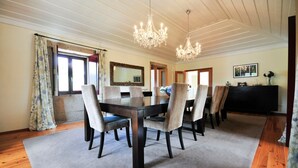 A dining area with a wooden table, six chairs, a chandelier, a large mirror, and a black cabinet. - Villa Alexa - Six Bedroom Villa, Sleeps 12 (Fornelos)