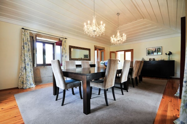 A dining area with a wooden table, six chairs, a chandelier, a large mirror, and a black cabinet. - Villa Alexa - Six Bedroom Villa, Sleeps 12 (Fornelos)
