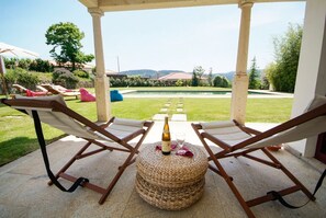 Un espacio de descanso al aire libre con dos sillones, un reposapiés tejido y una botella de champán.