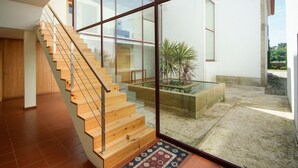 Un intérieur moderne avec un escalier en bois menant à une porte vitrée qui donne sur une cour.