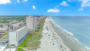 A coastal cityscape with a wide beach, high-rise buildings, and a clear sky.